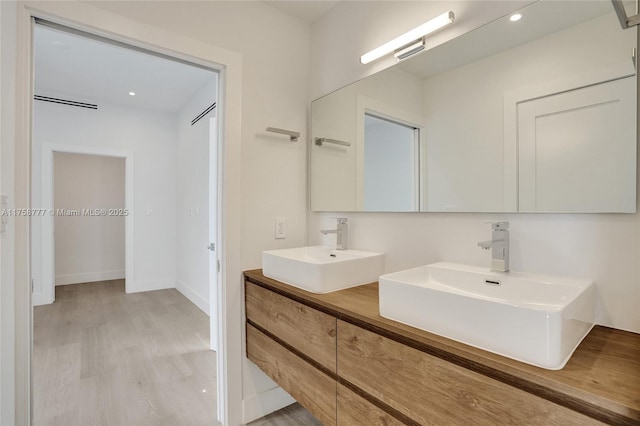 full bathroom with double vanity, wood finished floors, baseboards, and a sink