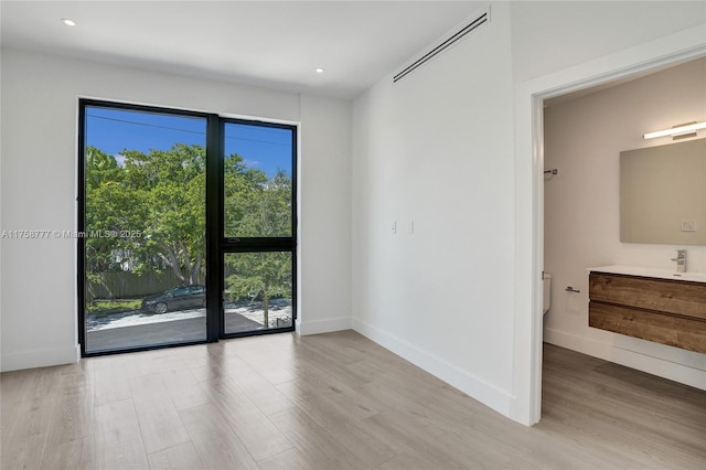 unfurnished room featuring baseboards, light wood-style flooring, recessed lighting, and a sink