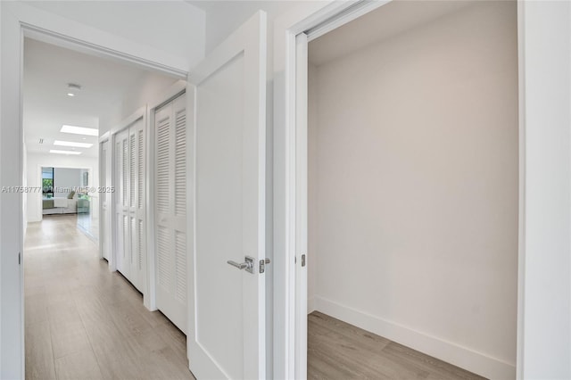 hall featuring baseboards and light wood-style floors