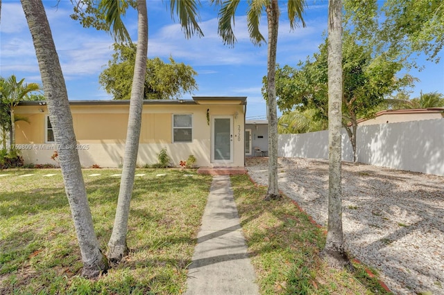 view of front of house featuring a front lawn, fence, and stucco siding