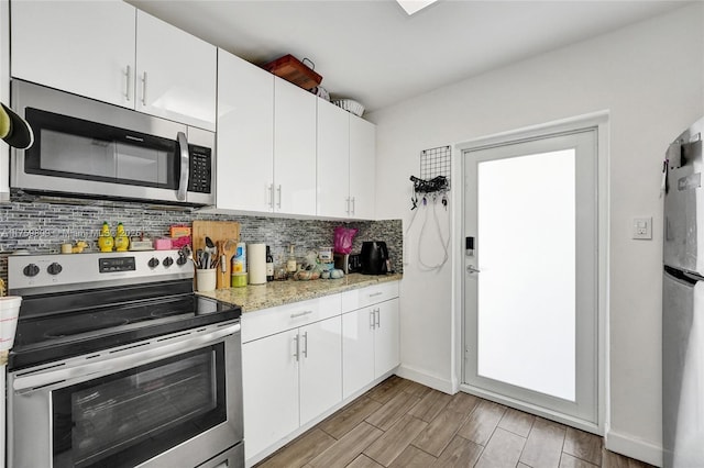 kitchen with decorative backsplash, white cabinets, appliances with stainless steel finishes, and wood tiled floor