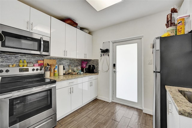 kitchen with light stone counters, backsplash, appliances with stainless steel finishes, white cabinets, and wood tiled floor