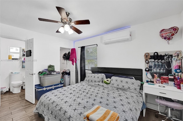 bedroom with wood finished floors, a ceiling fan, and a wall mounted AC