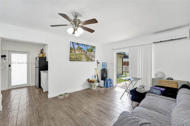 living area featuring ceiling fan, wood finished floors, baseboards, and a wall mounted AC