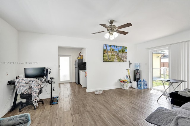 living room with light wood-type flooring, baseboards, and a ceiling fan