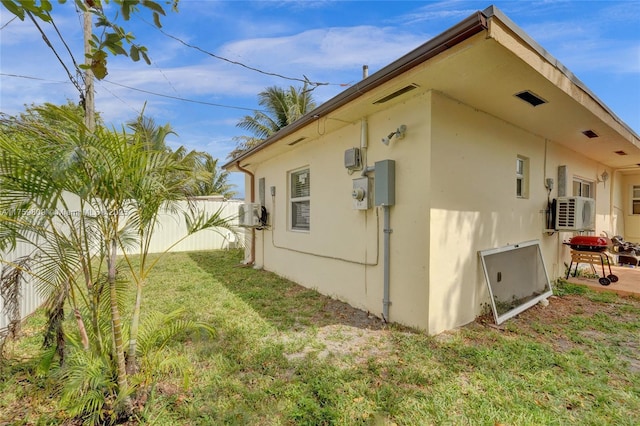 view of home's exterior featuring stucco siding, a lawn, and fence