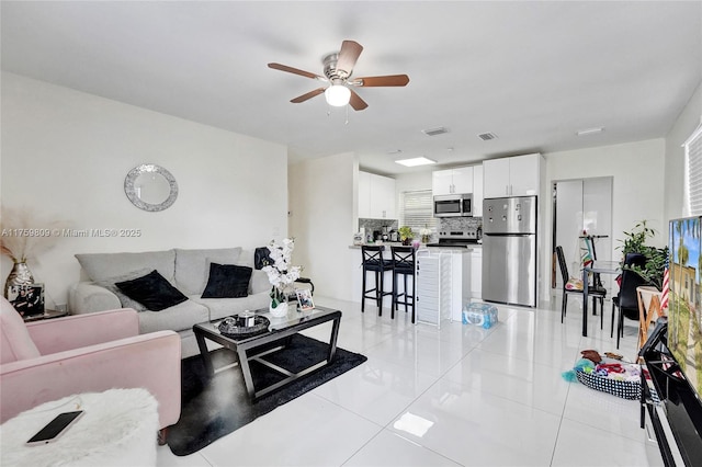 living area featuring light tile patterned floors, visible vents, and a ceiling fan