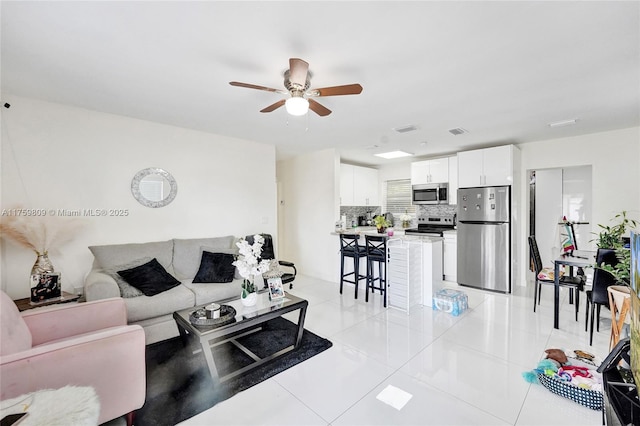 living room featuring light tile patterned flooring, visible vents, and ceiling fan