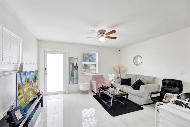 living area with light tile patterned floors and a ceiling fan