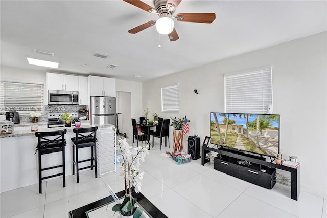 kitchen with visible vents, backsplash, light tile patterned floors, appliances with stainless steel finishes, and white cabinets