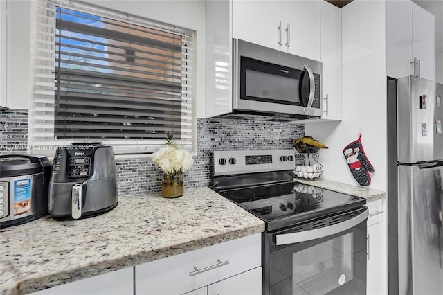 kitchen with white cabinets, backsplash, and stainless steel appliances