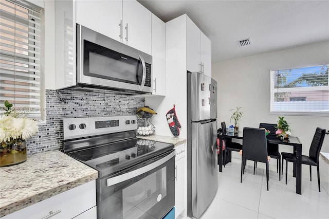 kitchen with visible vents, decorative backsplash, appliances with stainless steel finishes, light tile patterned flooring, and white cabinets