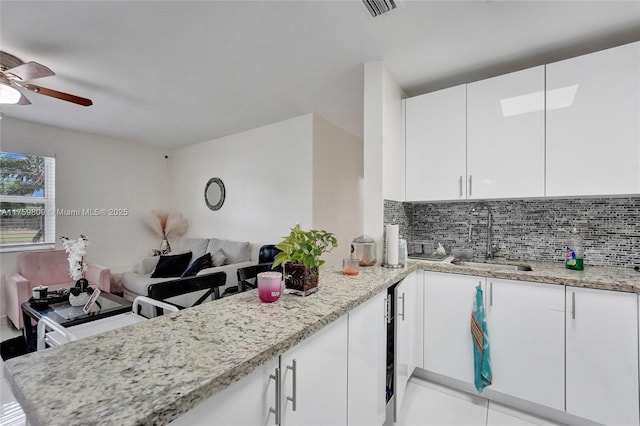 kitchen with open floor plan, backsplash, visible vents, and a sink