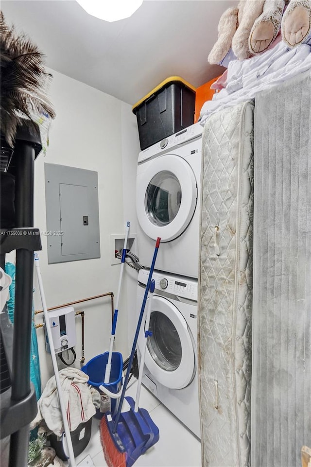 laundry area featuring electric panel, stacked washer and dryer, laundry area, and tile patterned flooring