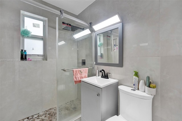 full bath with toilet, tile walls, a stall shower, and vanity