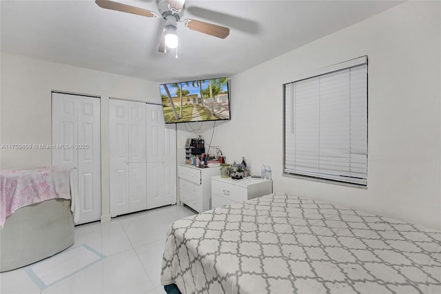 bedroom featuring light tile patterned floors, multiple closets, and a ceiling fan