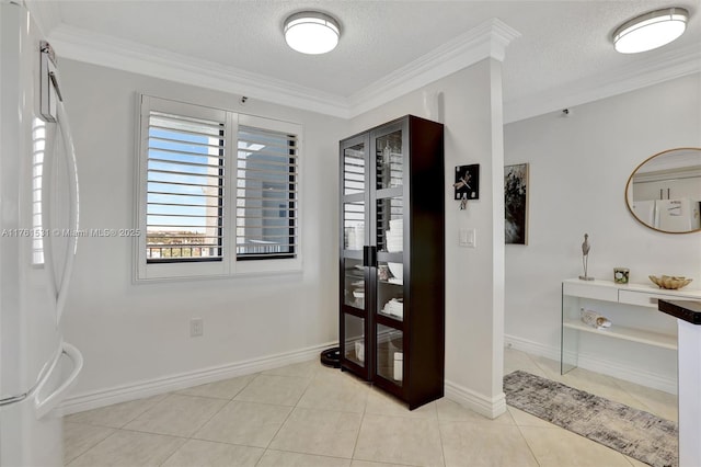 interior space featuring a textured ceiling, light tile patterned floors, baseboards, and ornamental molding