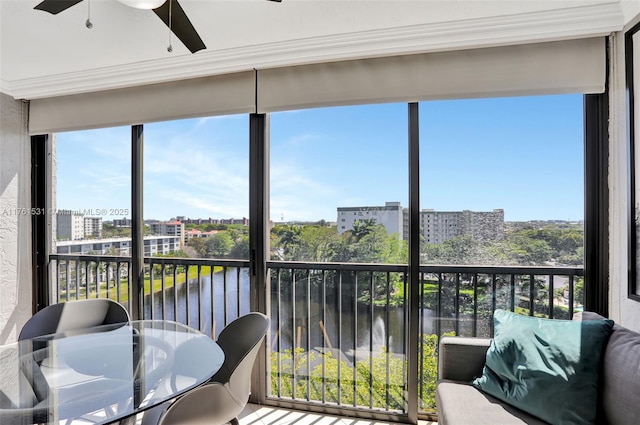 sunroom with a city view, a water view, and ceiling fan