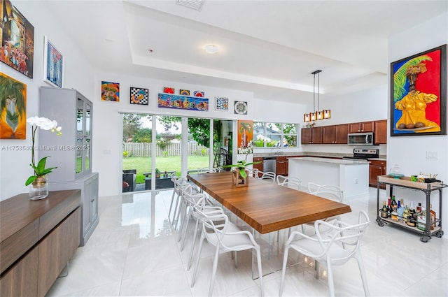 dining room featuring light tile patterned floors and a raised ceiling