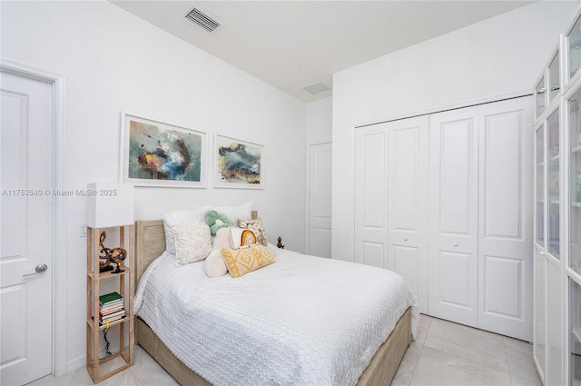 bedroom featuring marble finish floor, visible vents, and a closet