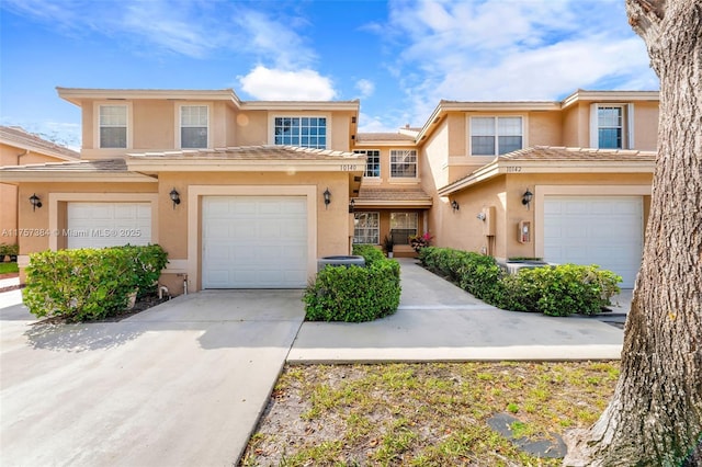 multi unit property featuring a tiled roof, an attached garage, driveway, and stucco siding