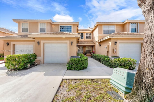 multi unit property with stucco siding, a tiled roof, concrete driveway, and a garage