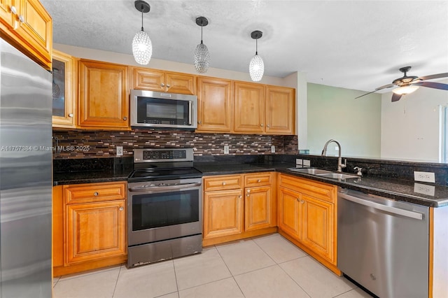 kitchen featuring light tile patterned floors, decorative backsplash, a peninsula, stainless steel appliances, and a sink