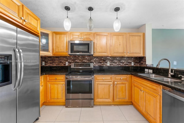 kitchen featuring a sink, backsplash, stainless steel appliances, light tile patterned floors, and hanging light fixtures