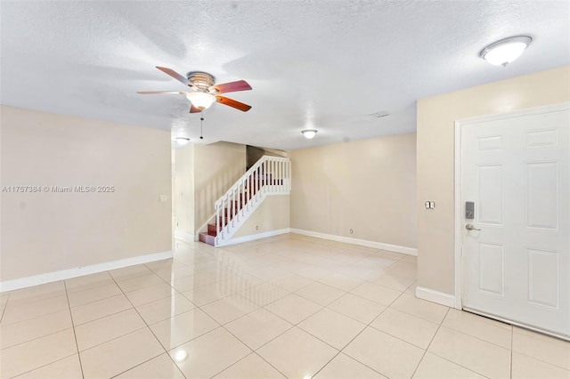 spare room with light tile patterned flooring, stairway, baseboards, and a ceiling fan