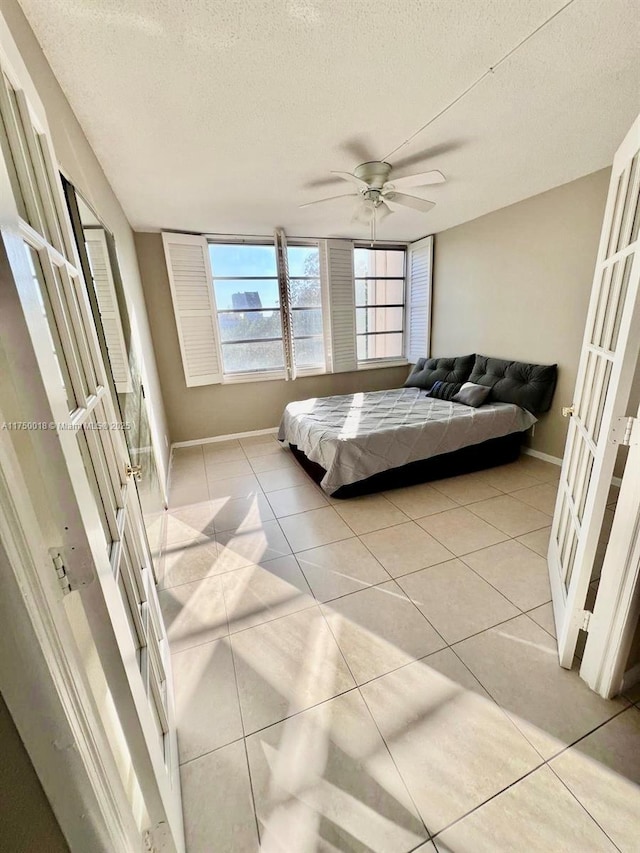 bedroom with light tile patterned flooring, french doors, baseboards, and a textured ceiling