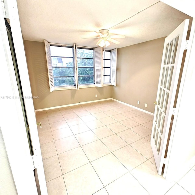 spare room featuring baseboards, a textured ceiling, ceiling fan, and light tile patterned flooring