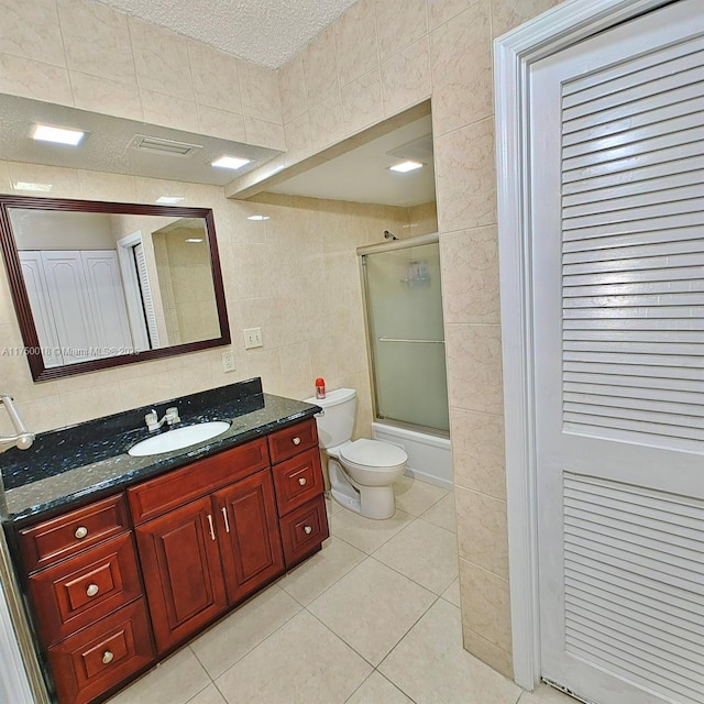 bathroom featuring toilet, a textured ceiling, tile walls, tile patterned flooring, and vanity