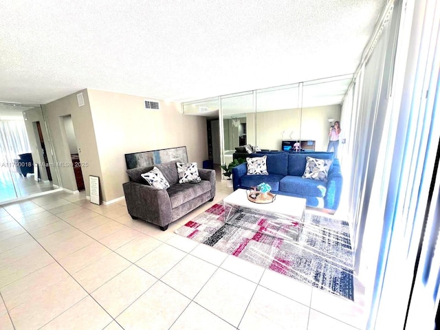 living room with light tile patterned flooring, visible vents, and a textured ceiling