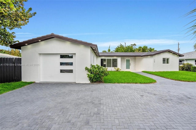 ranch-style house with a front lawn, decorative driveway, fence, and a garage