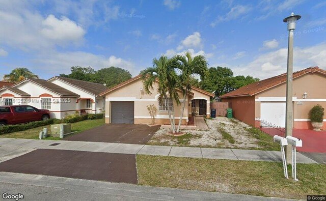 view of front of property with stucco siding, an attached garage, and driveway