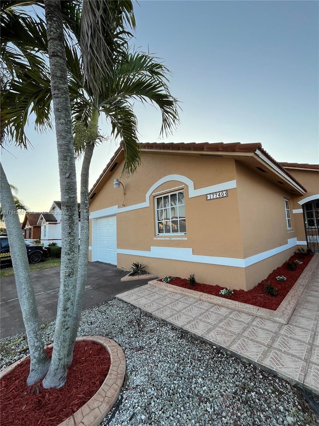 view of property exterior featuring stucco siding, an attached garage, and a tiled roof