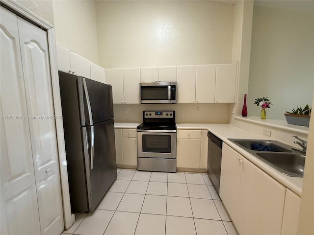 kitchen with a sink, appliances with stainless steel finishes, light tile patterned flooring, and light countertops