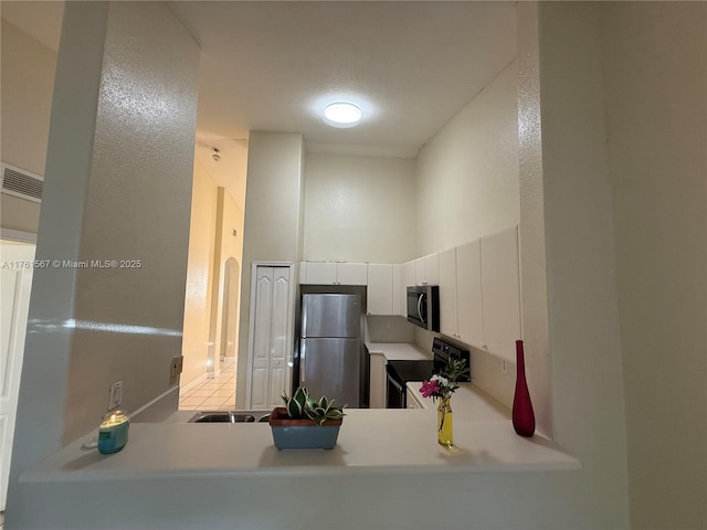 kitchen featuring light countertops, a high ceiling, and appliances with stainless steel finishes