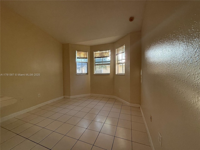 spare room featuring baseboards and light tile patterned flooring