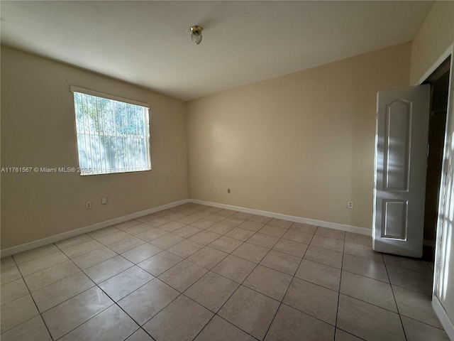 empty room featuring light tile patterned floors and baseboards