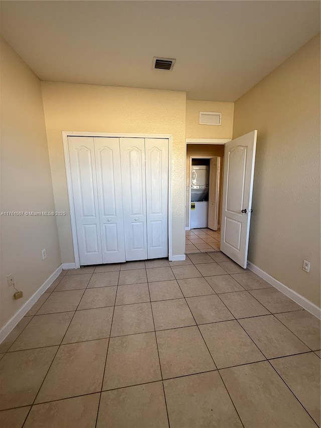 unfurnished bedroom with light tile patterned floors, visible vents, a closet, and baseboards