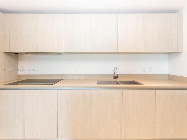 kitchen with a sink, light countertops, modern cabinets, and light brown cabinetry