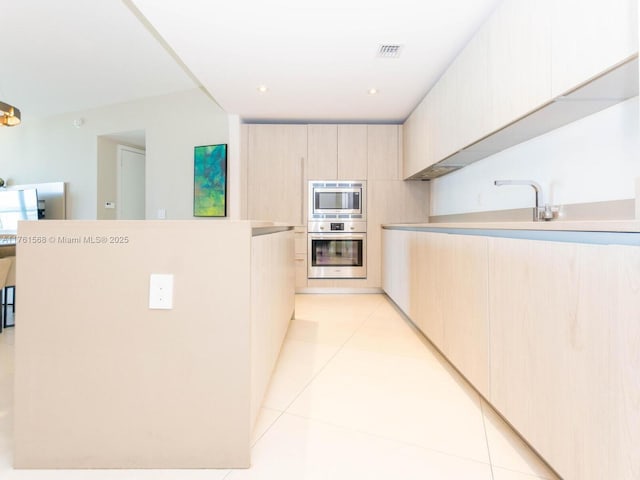 kitchen with light tile patterned floors, light brown cabinets, stainless steel appliances, and light countertops