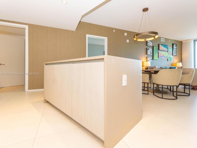 kitchen featuring light tile patterned floors, pendant lighting, and wallpapered walls