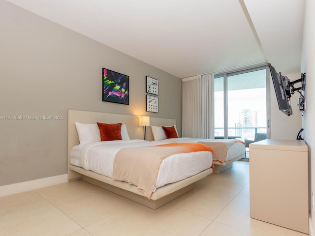 bedroom with light tile patterned flooring, a wall of windows, and baseboards