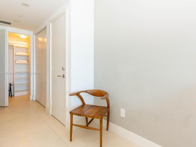 corridor with light tile patterned floors, visible vents, and baseboards