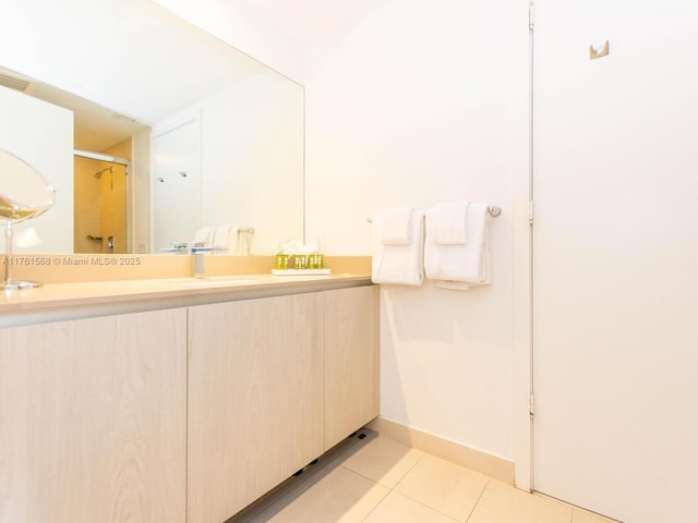 bathroom featuring tile patterned flooring, vanity, baseboards, and a shower