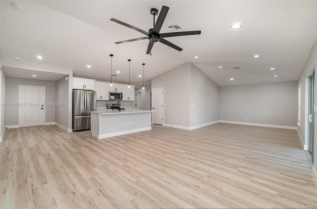 unfurnished living room with light wood-type flooring, baseboards, and vaulted ceiling