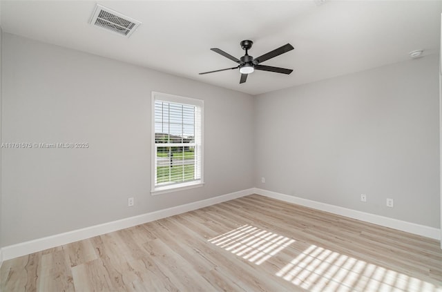 empty room featuring a ceiling fan, wood finished floors, visible vents, and baseboards