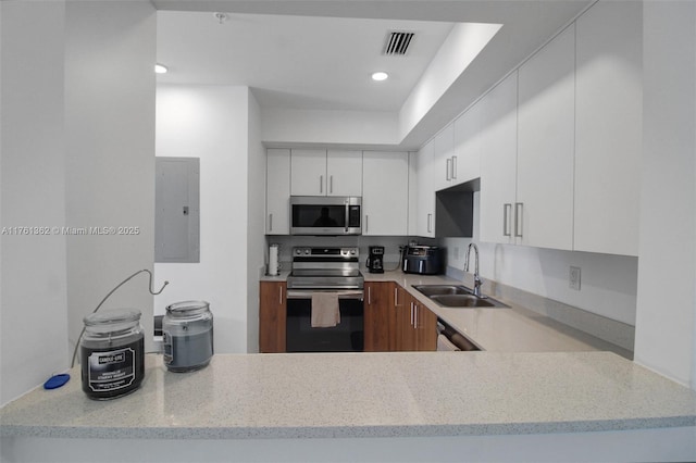 kitchen featuring visible vents, light stone countertops, electric panel, stainless steel appliances, and a sink